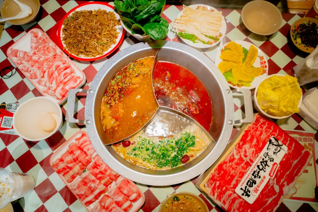 Hotpot restaurant with a spread of enoki mushrooms, beef, lamb, fried rice, and vegetables