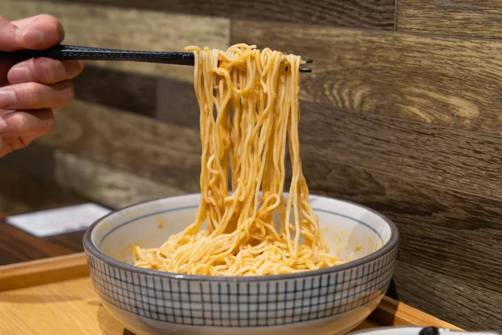 Crab roe noodles pulled up by chopsticks