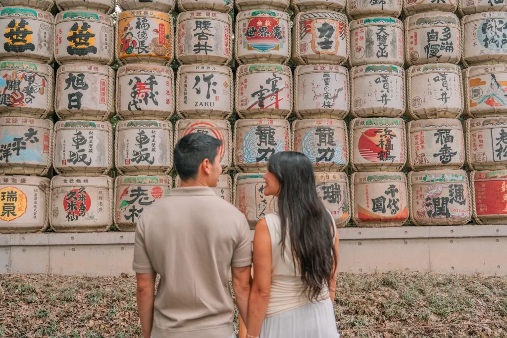 Angelia and Chris standing in front of the sake barrels at Meiji Jingu
