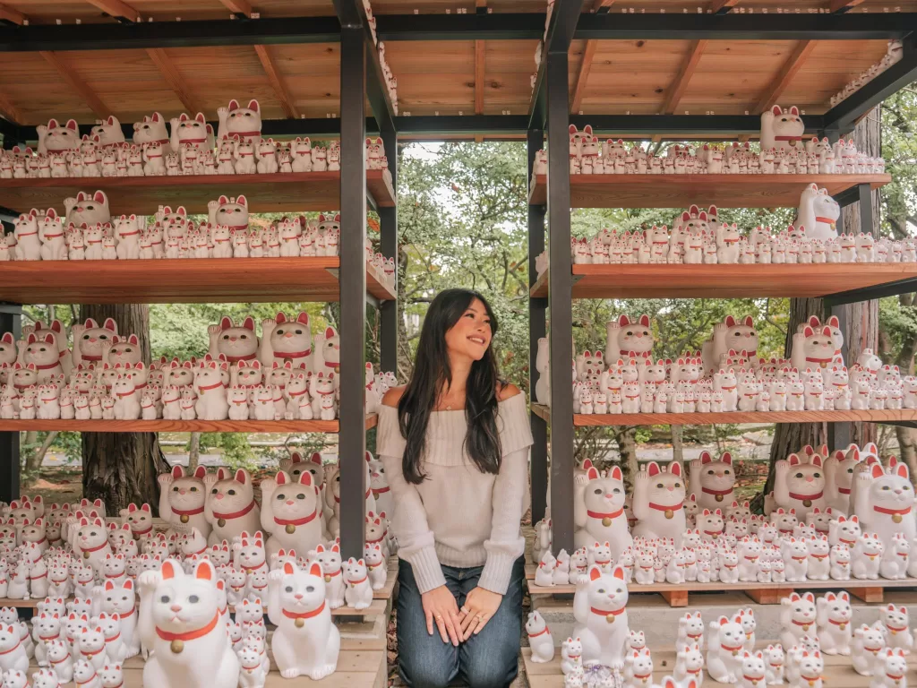 Angelia standing around the cat figurines at Gotokuji Temple