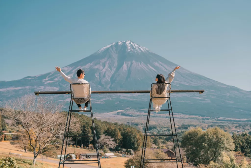 Angelia and Chris sitting on high chairs at Makaino Farms posing in front of Mt. Fuji