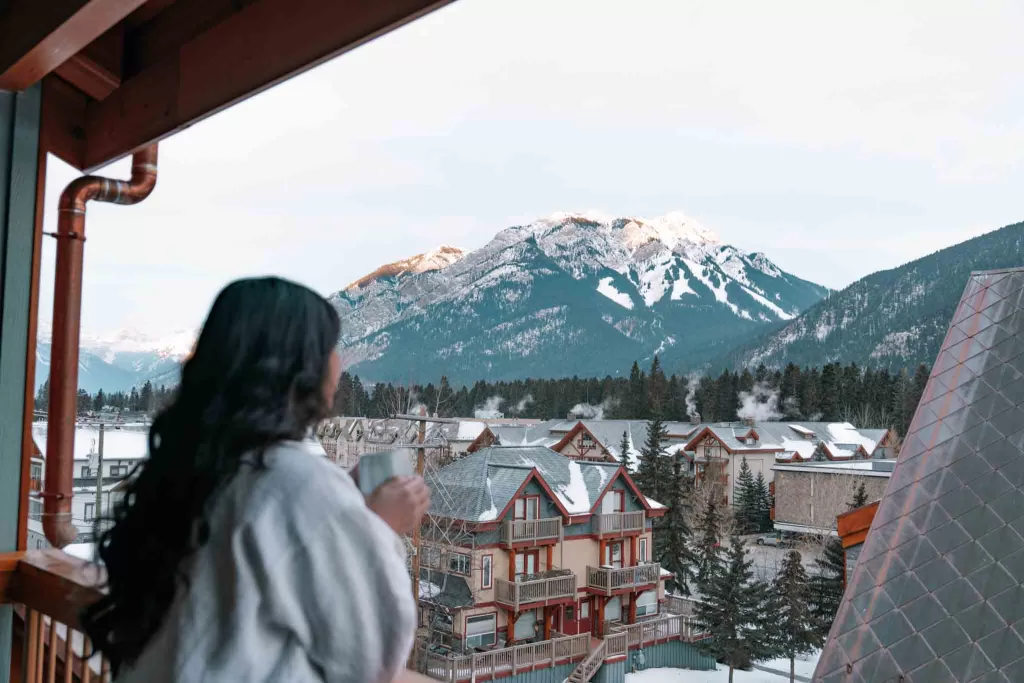 Angelia holding a cup of coffee and staring at the mountains at the Otter Hotel