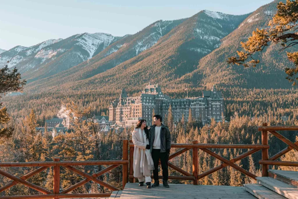 Angelia & Chris posing in front of Fairmont Banff Springs at Surprise Corner
