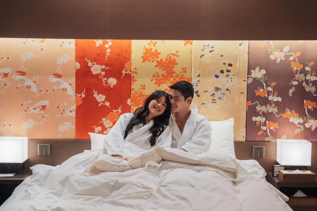 Angelia & Chris laying in bed at Hyatt Regency in Kyoto