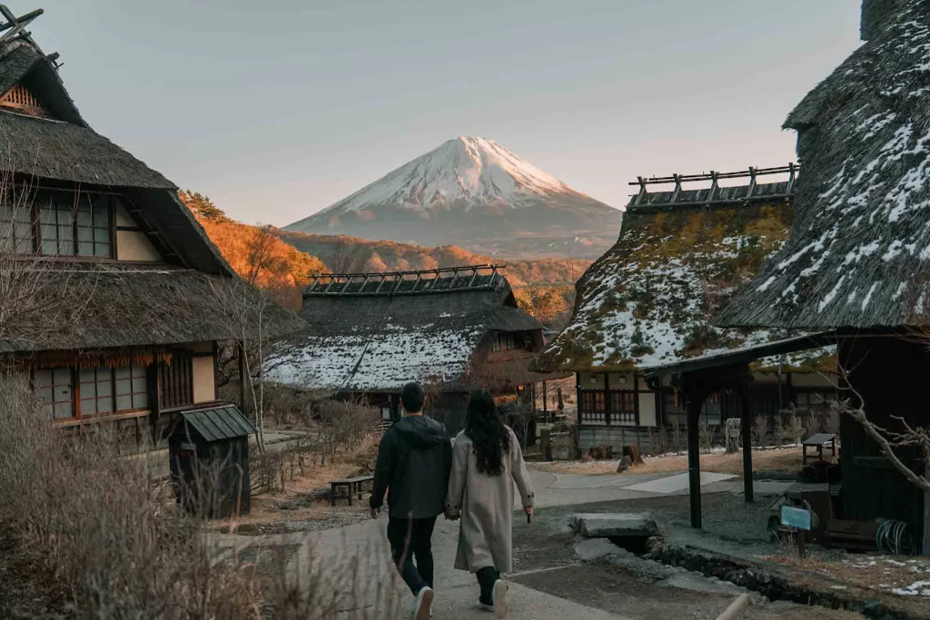 Angelia and Chris holding hands walking through Saiko Iyashi-no-Sato Nemba traditional village in front of Mt. Fuji