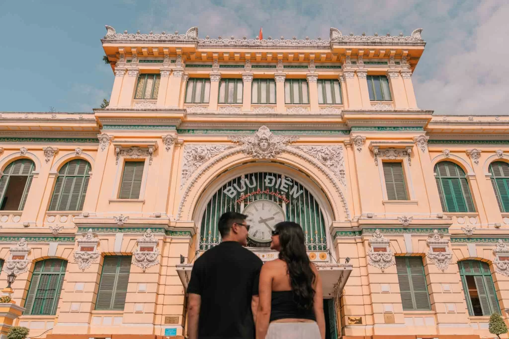 Angelia & Chris holding hands in front of Saigon Central Post Office